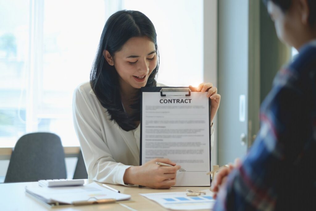 Before selling a house, the broker explains the contract to the client, pointing to the signature in the paperwork