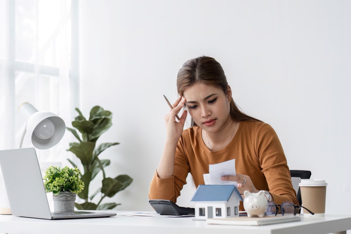 Young Woman Stressed While Selling a House, Working at Desk with Laptop