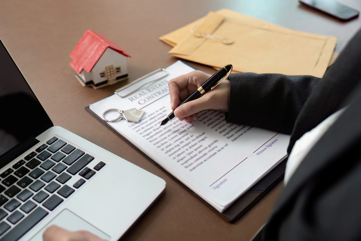 Lawyer signing real estate contract at desk