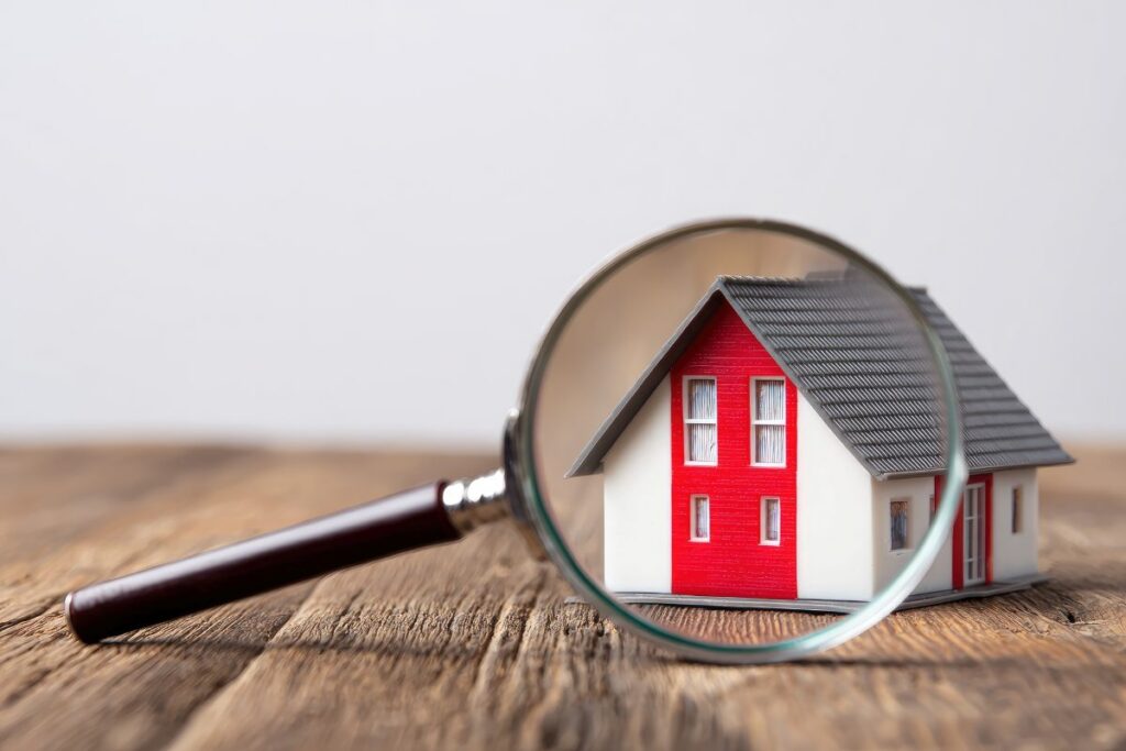 A house model is seen through a magnifying glass on a wooden table