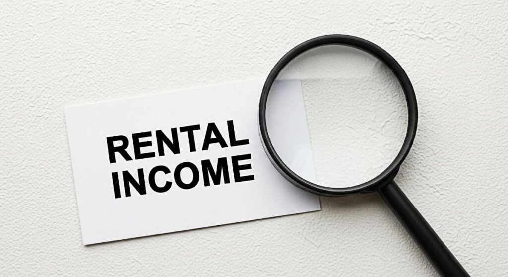 Closeup of a magnifying glass examining a card with the words Rental Income on a textured white surface symbolizing financial investigation and the importance of understanding property investment retu