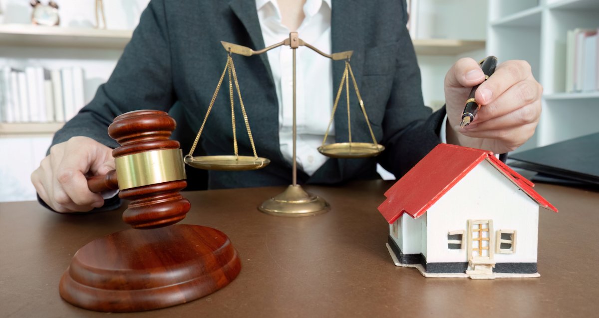 Lawyer with scales of justice and miniature house for real estate