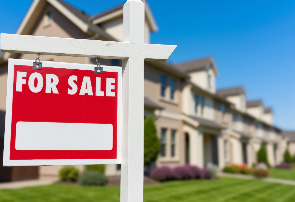 A red and white 'For sale' sign in front of a row of houses