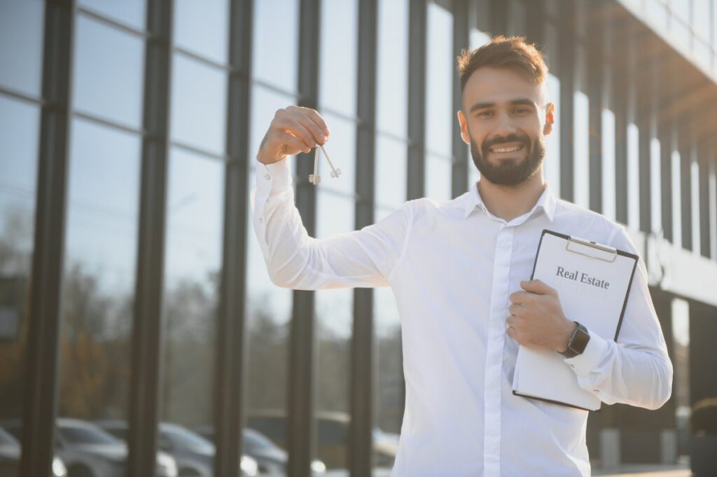 Real estate attractive agent beautiful man with house keys in front of sold apartment