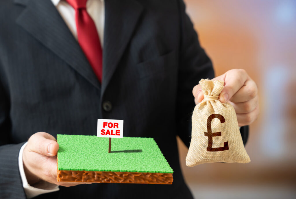 Plot of land for sale with a British pound symbol and money bag, representing land investment and property value