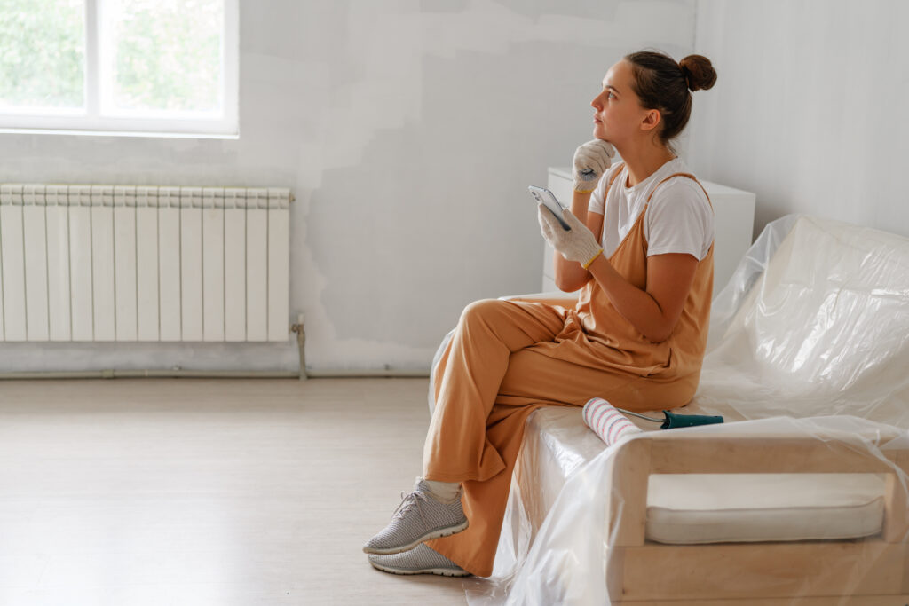Woman sitting on a covered sofa in a nearly empty room during a move or relocation