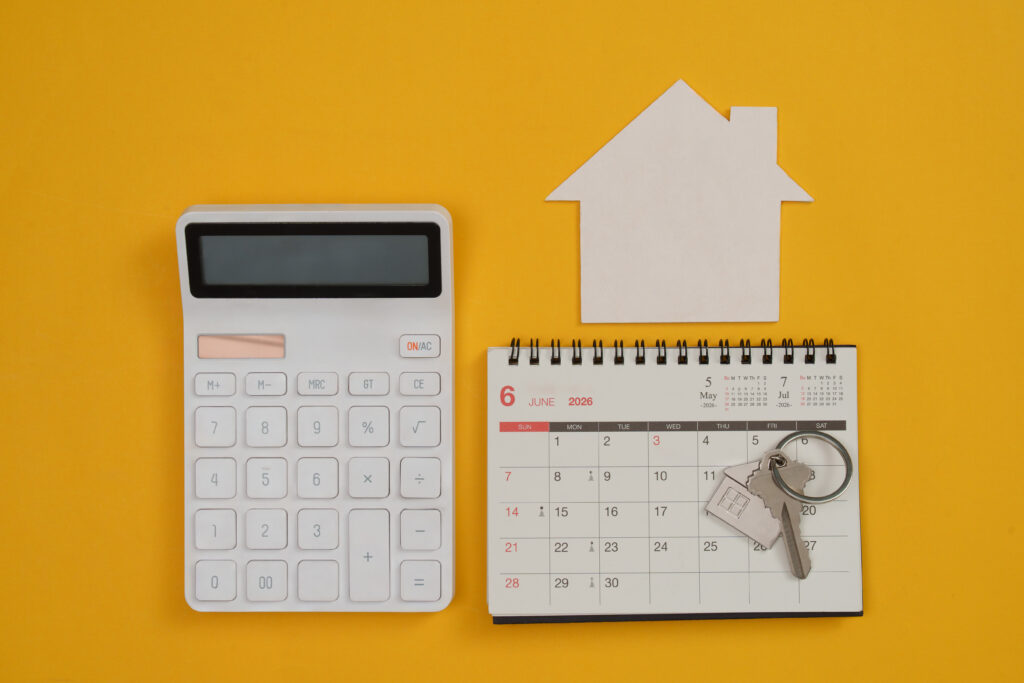 Home-buying concept with a calendar, calculator, house keys, and property documents