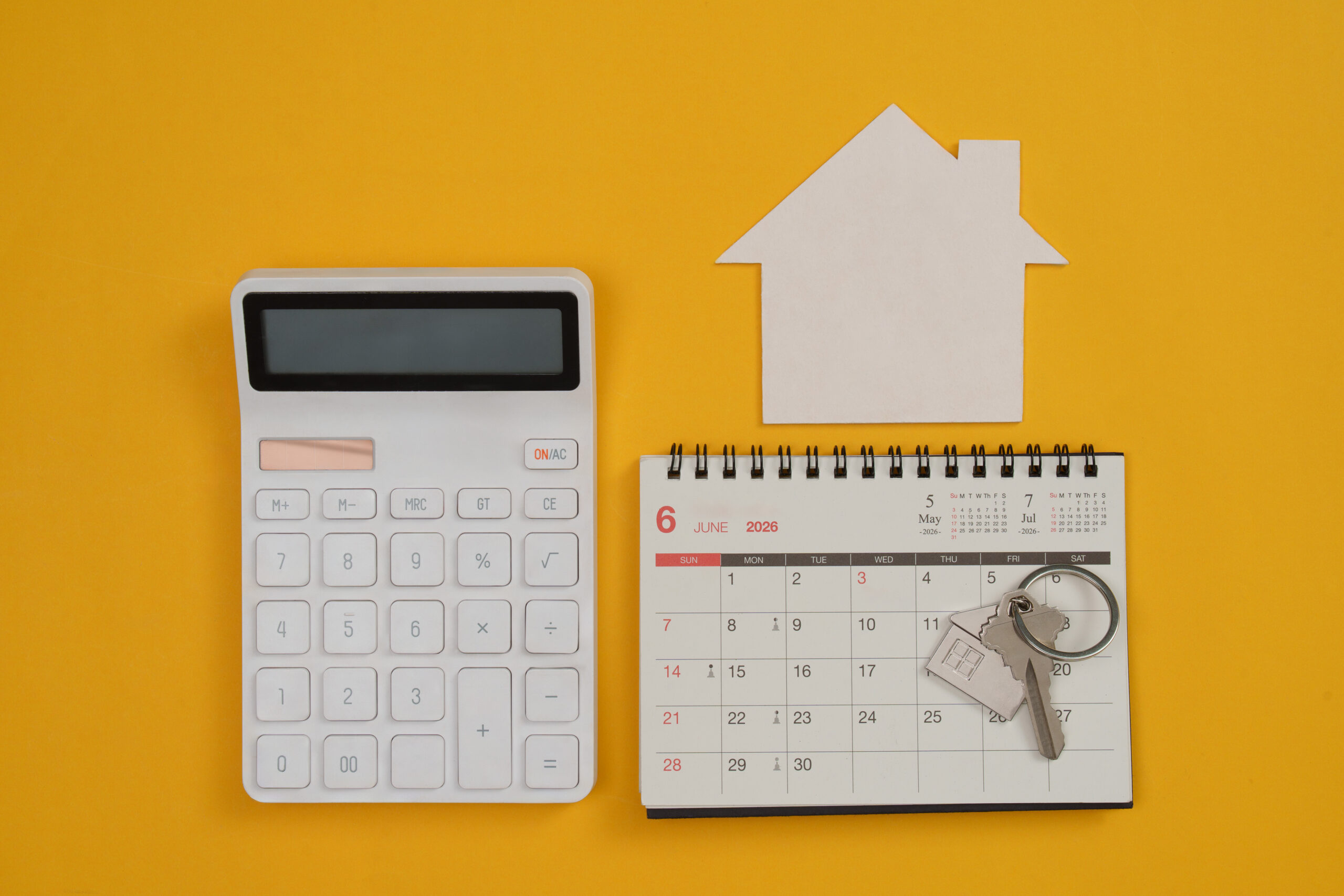 Home-buying concept with a calendar, calculator, house keys, and property documents