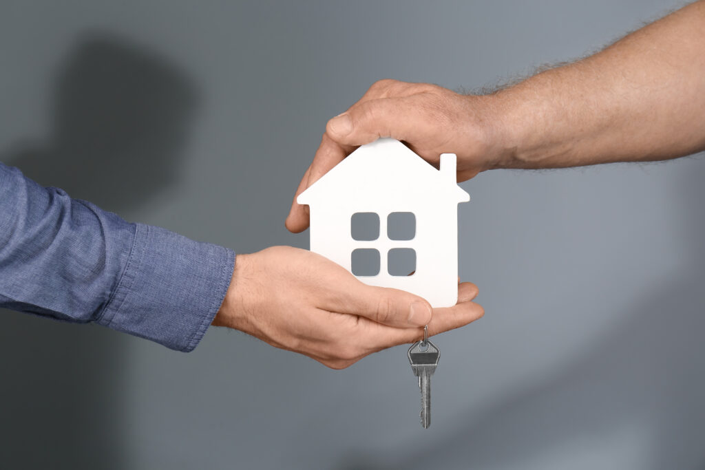Real estate agent with a senior man holding a house model and discussing property options