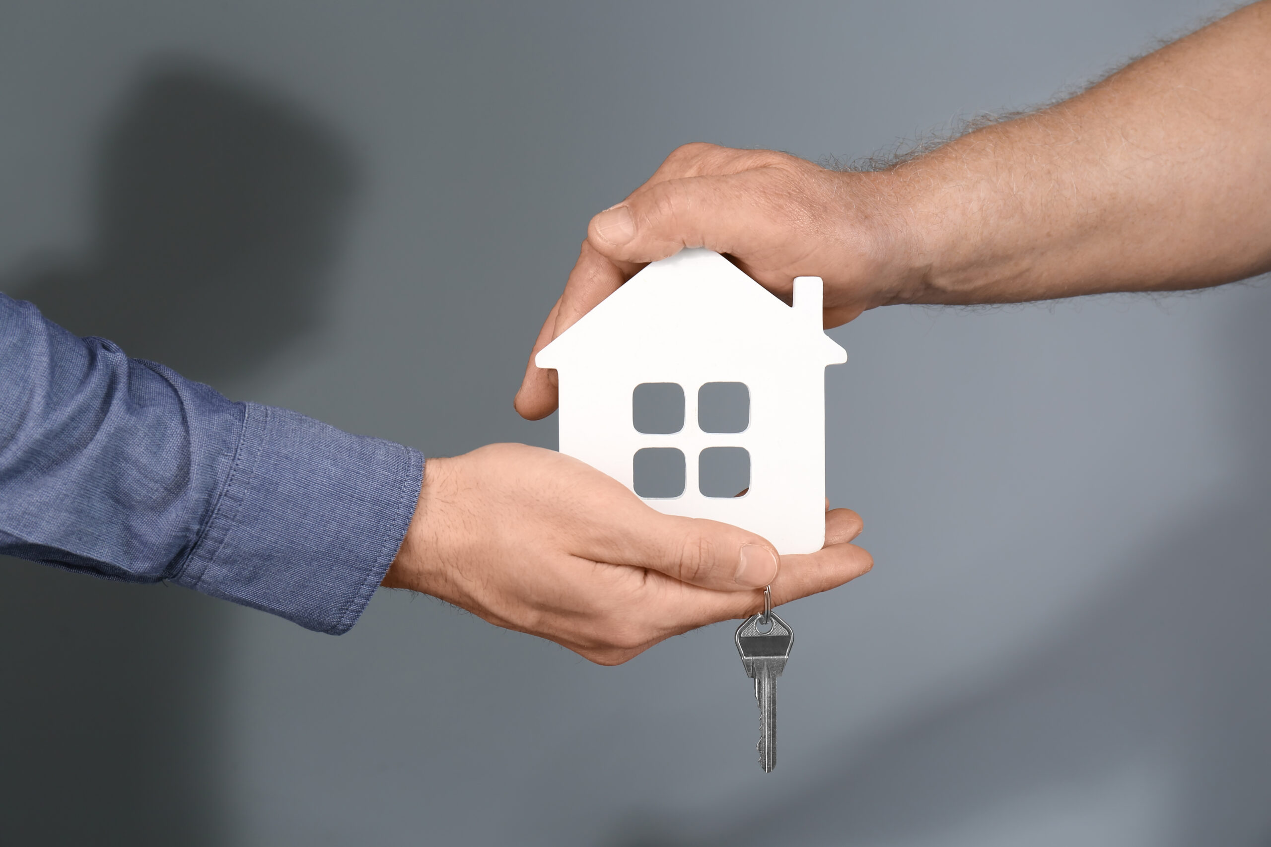 Real estate agent with a senior man holding a house model and discussing property options