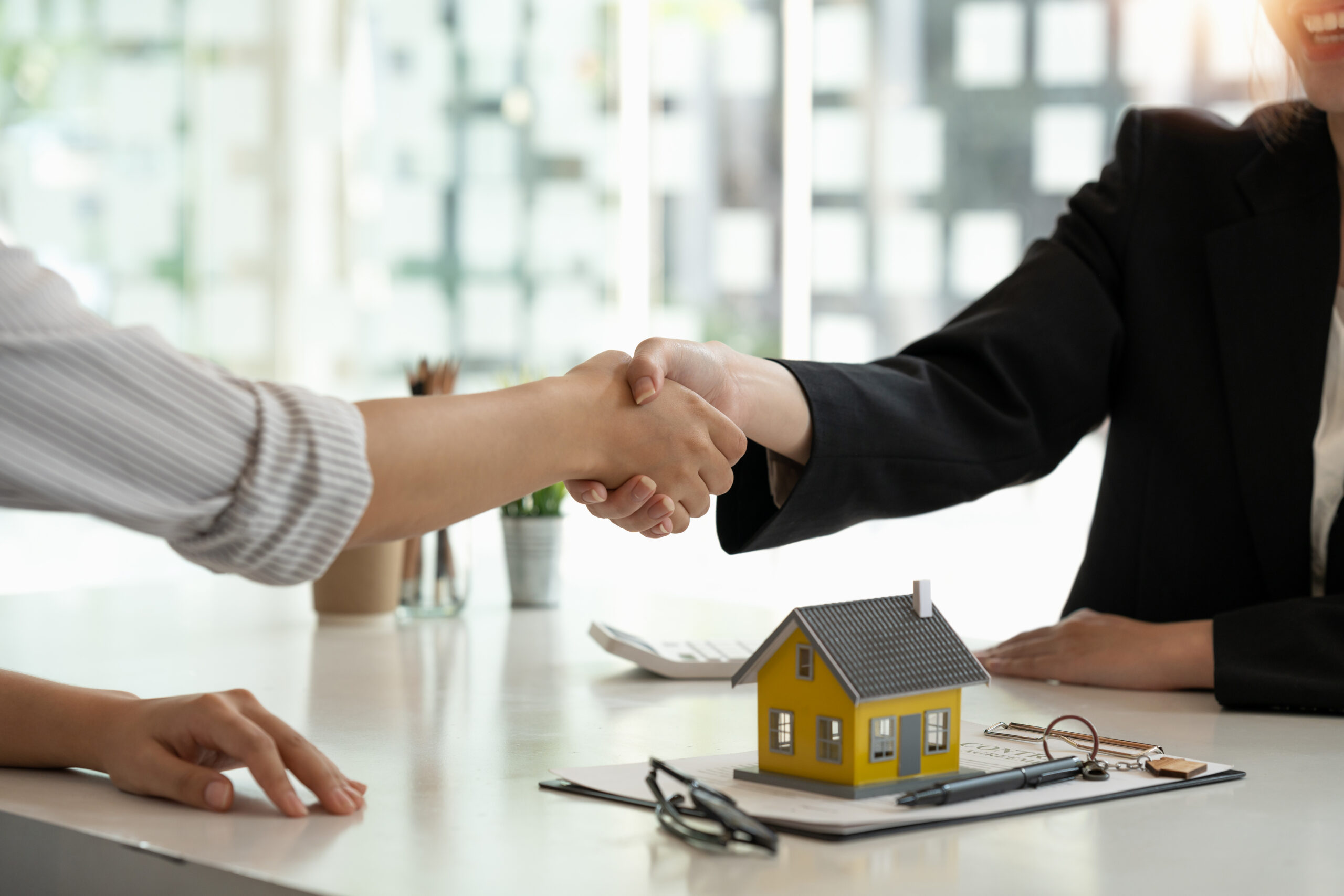 Real estate broker and customer shaking hands after signing a property agreement