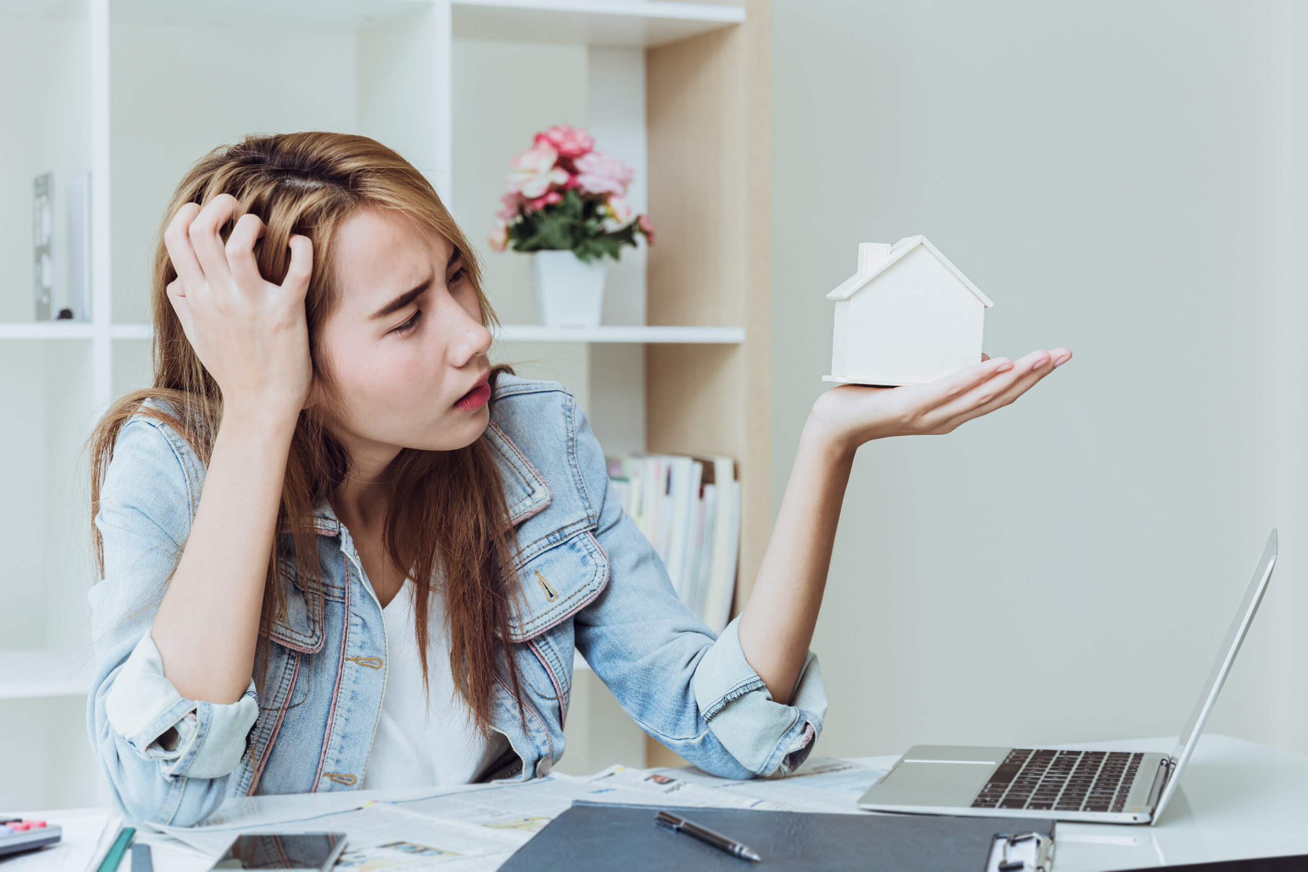 Young woman working at a business office desk, appearing stressed while handling work tasks
