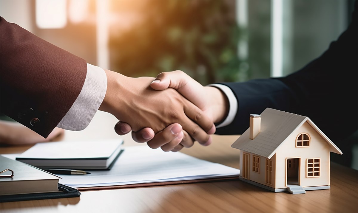 Estate agent shaking hands with a buyer after signing a property agreement.