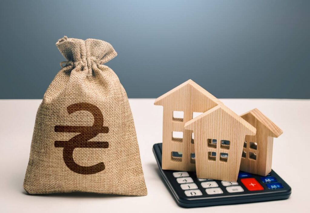 Houses on a calculator beside a Ukrainian hryvnia money bag.