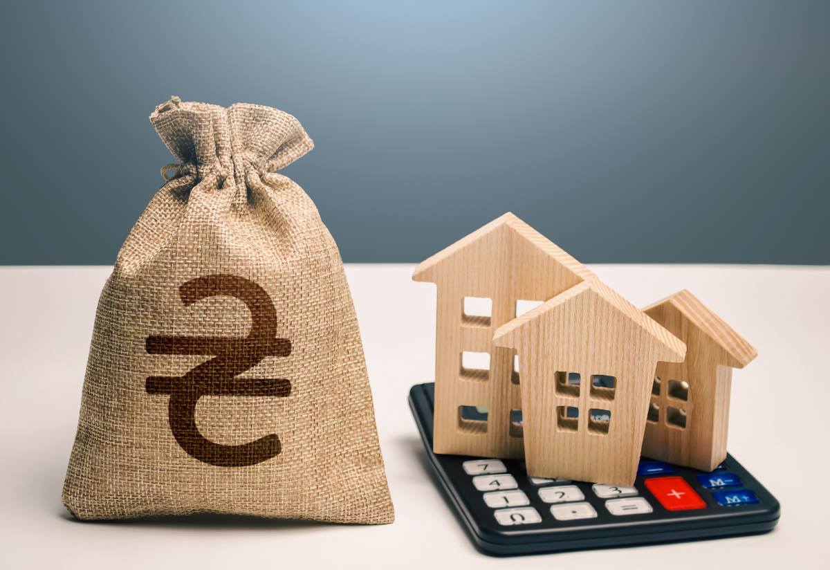 Houses on a calculator beside a Ukrainian hryvnia money bag.