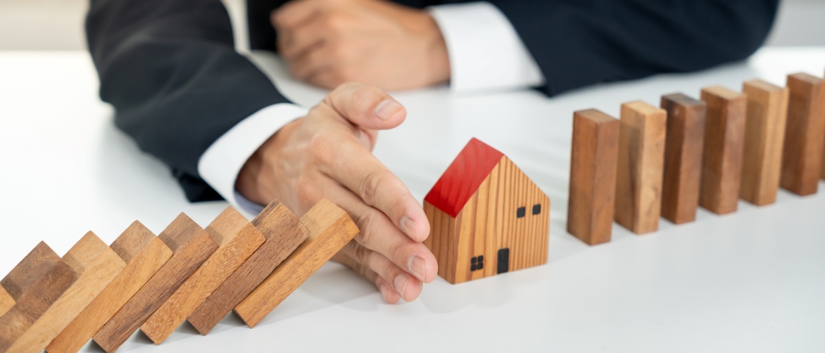Hands protecting dominoes, representing insurance and risk protection.