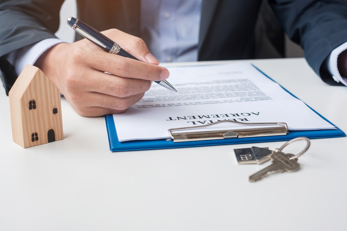 Man signing a home contract agreement and property documents.