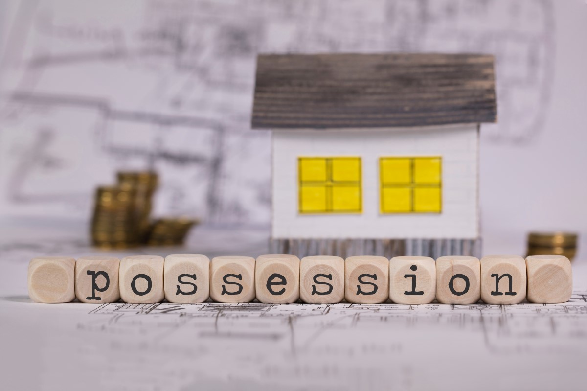 Wooden letters spelling “possession” beside a small paper house.