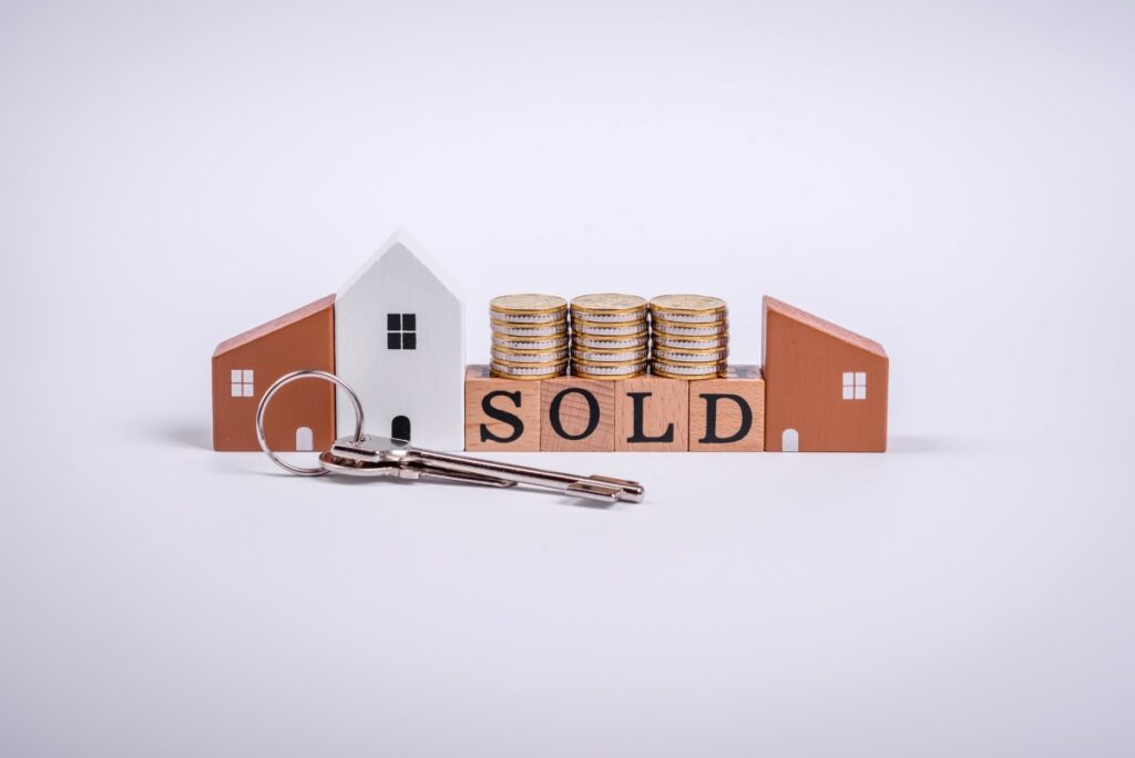 The inscription Sold made of wooden cubes on a plain background