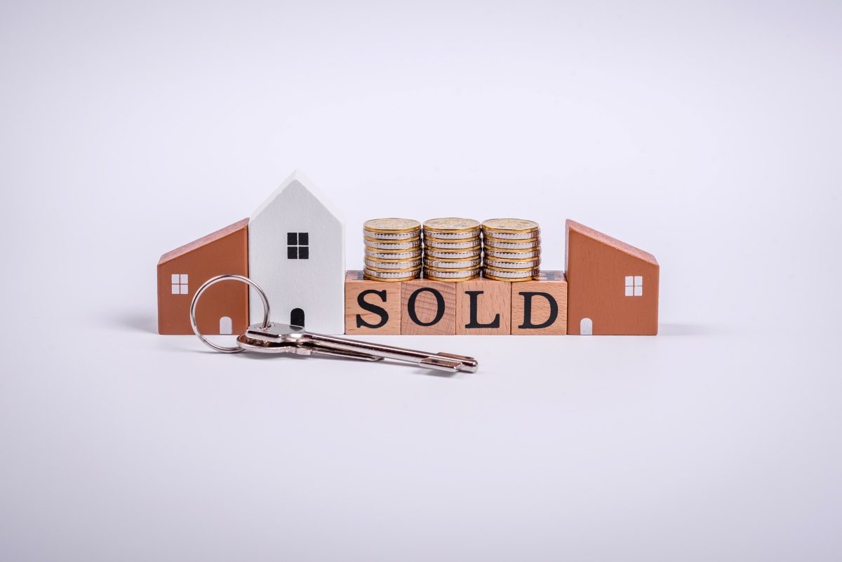 The inscription Sold made of wooden cubes on a plain background