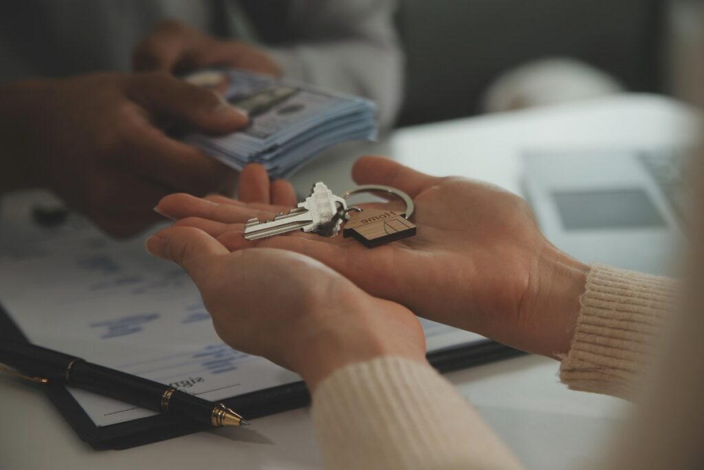 Real estate agent home sales broker is using a pen pointing to the house model and explains the business contract