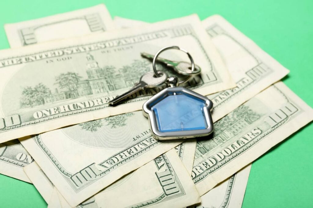 Keys from house with keychain and money on color background, closeup