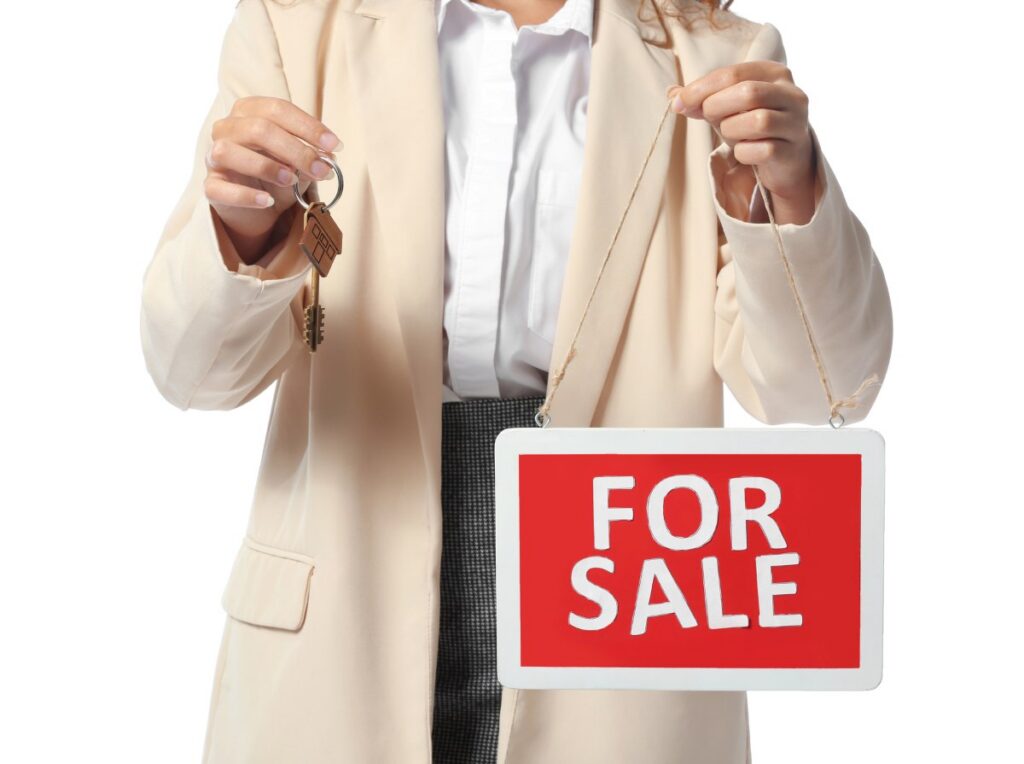African American real estate agent with For Sale sign and key on white background