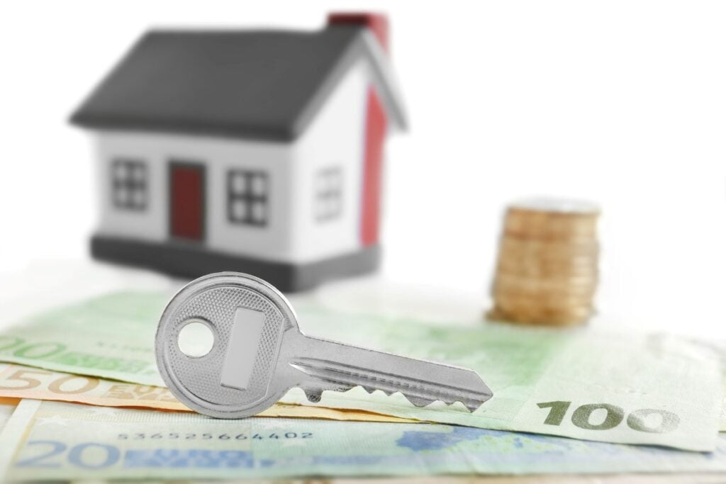 Key with money and toy house, close up Insurance broker concept