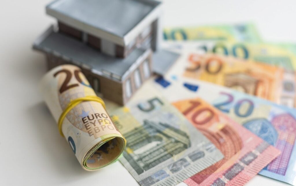 Model of cardboard house with key and dollar bills. Building, loan, real estate, cost of housing or buying a home concept