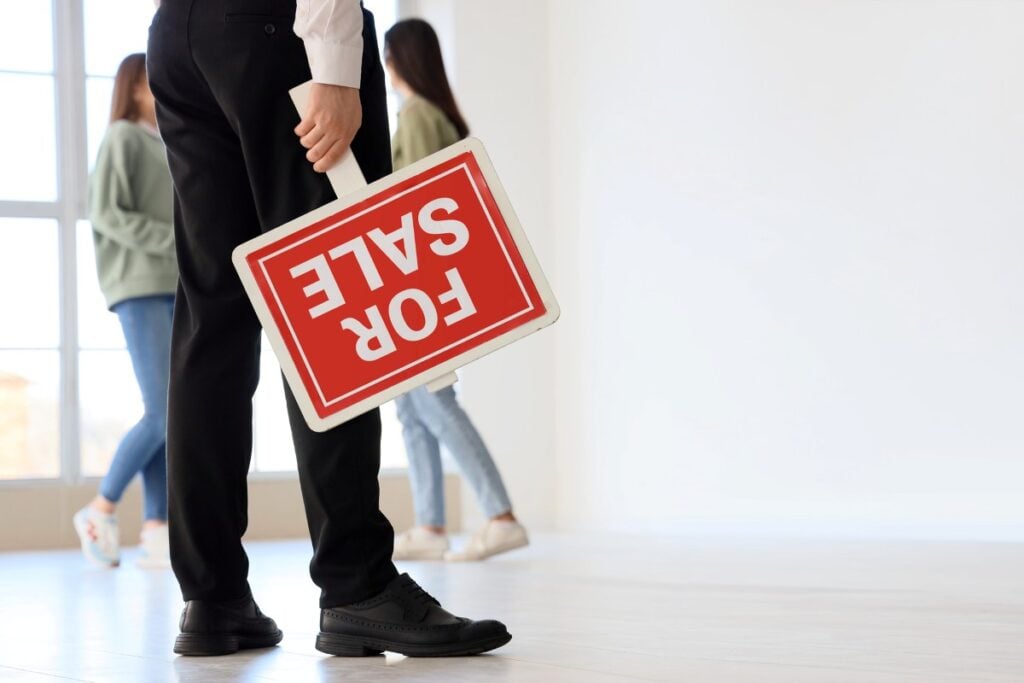Real estate agent with FOR SALE sign in flat