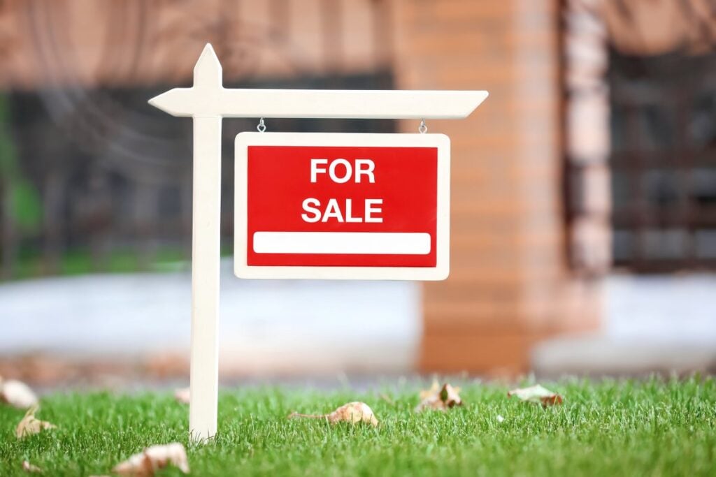 For sale sign on lawn near house
